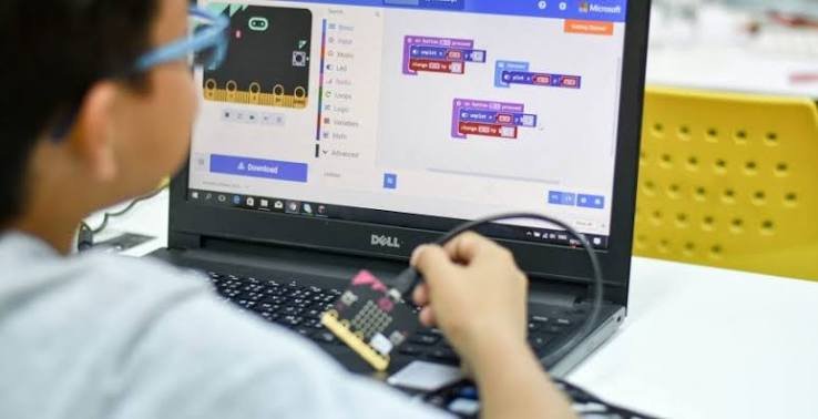 Student learning to code with a micro:bit and laptop